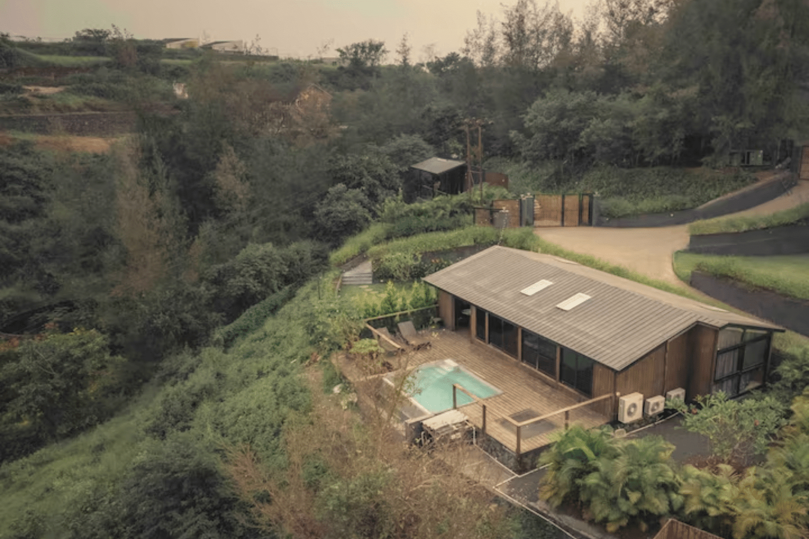 Aerial view of a modern pool villa in a lush, green landscape.