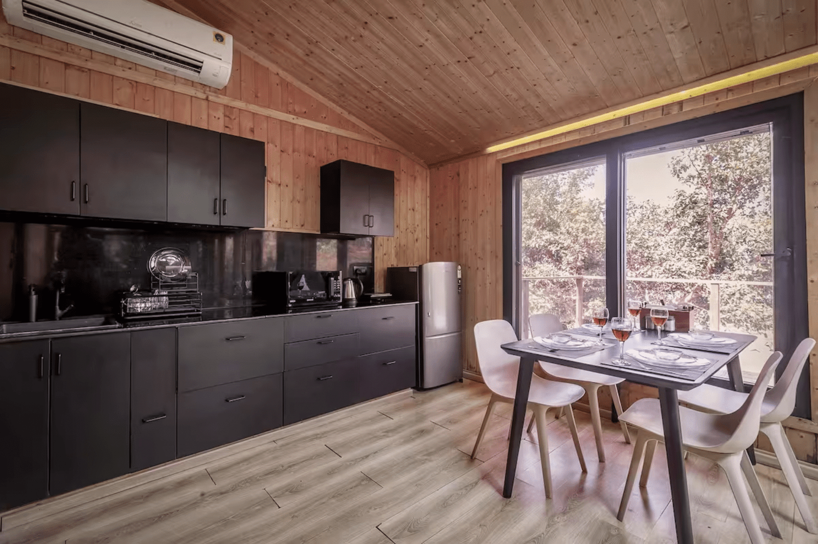 Modern villa kitchen and dining area with black cabinets and forest views.