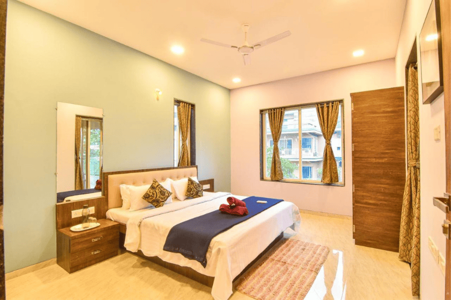 Spacious, elegant bedroom with king bed, side tables, and large windows for luxury stay in Lonavala.