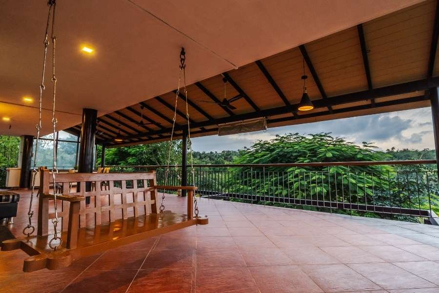 Covered outdoor veranda with a wooden swing at a Luxury Villa in Nashik.