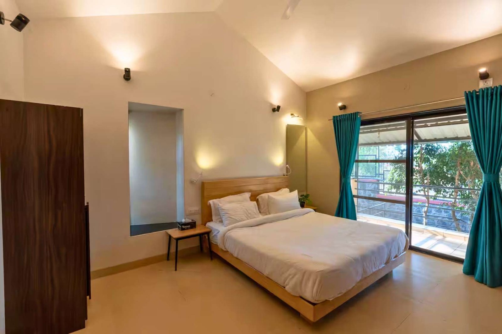 Bright bedroom in Panchgani bungalow, with modern décor and balcony access.