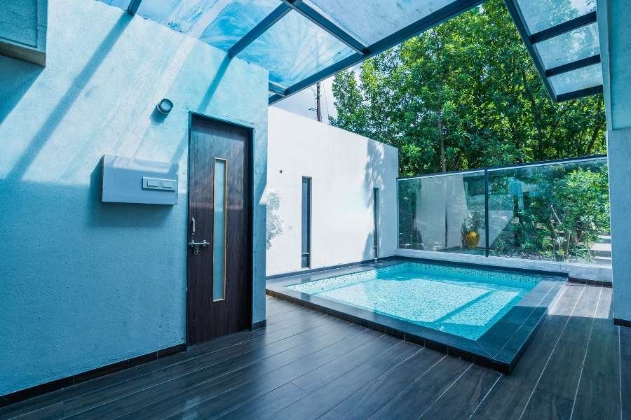 Luxury modern pool villa in Nashik with a private glass-roof plunge pool, surrounded by greenery and sleek minimalist architecture.