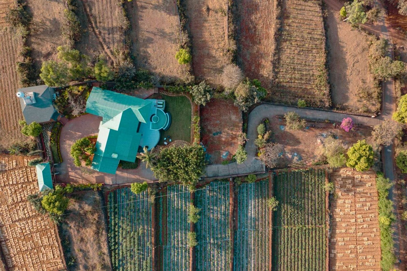 Aerial view of villa in Panchgani, surrounded by terraced farmland and greenery.