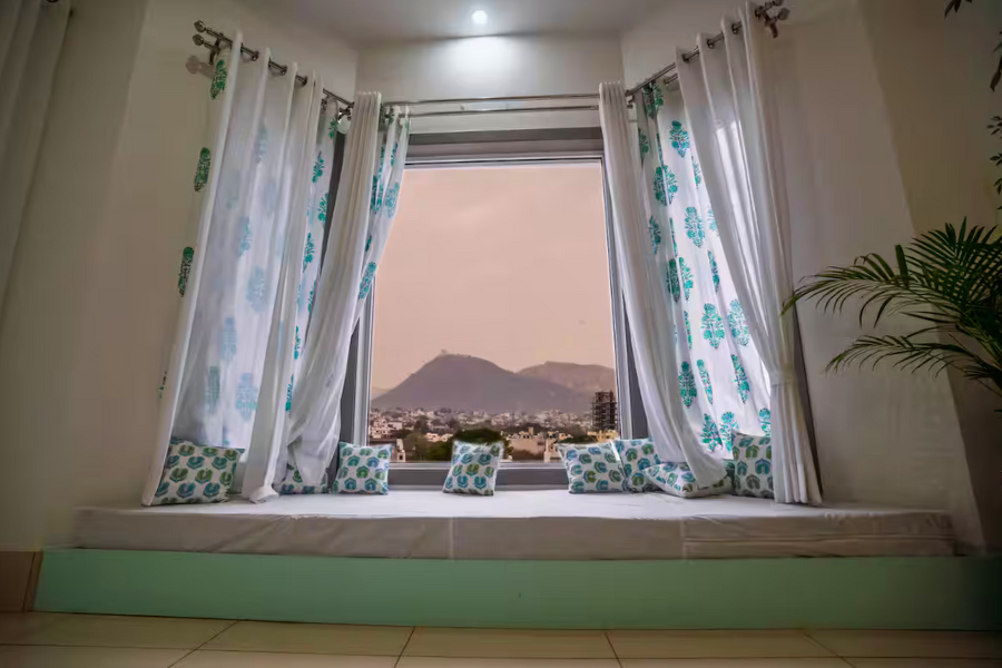 Private villa interior with cozy setup and rain visible through glass doors.